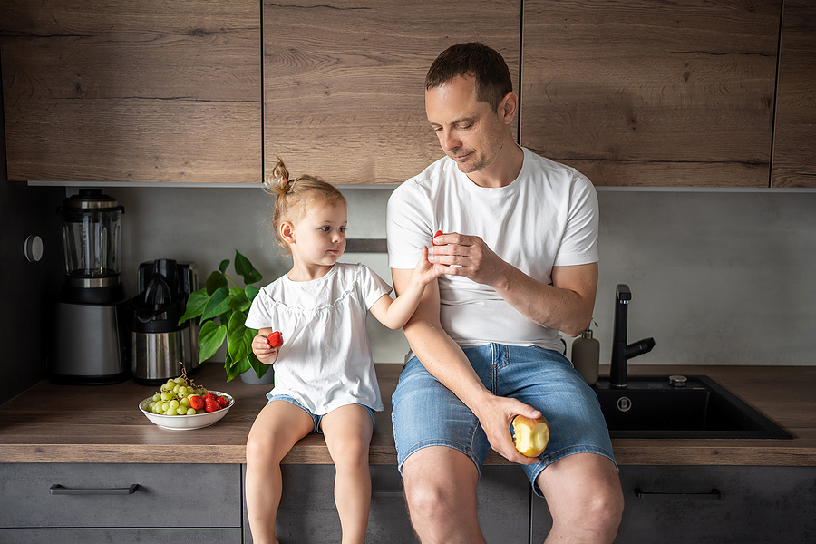 Cute little girl and her dad are eating fruit
